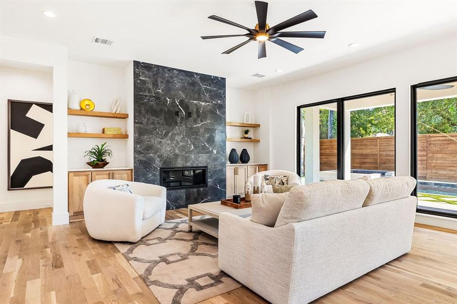 Living room featuring a fireplace, light wood-type flooring, ceiling fan, and recessed lighting Living room featuring a fireplace, light wood-type flooring, ceiling fan, and recessed lighting