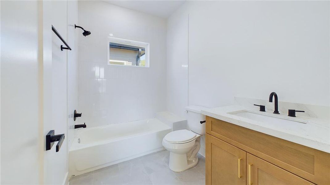 This stylish ensuite bath showcases elegant finishes throughout. A spacious vanity is lined with calacatta quartz with an under-mount sink and added storage is topped with gold hardware while the tub and shower combo is framed by classic white subway tiles, creating a clean and timeless look.