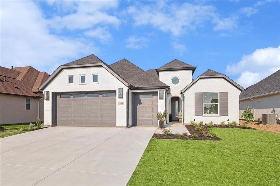 View of front of property featuring a front lawn and a garage