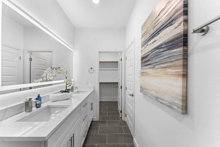 Full bath with double vanity, dark tile patterned floors, and a walk in closet Full bath with double vanity, dark tile patterned floors, and a walk in closet