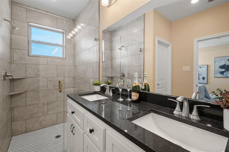 Bathroom featuring a dual-sink vanity with a dark countertop and white cabinetry Bathroom featuring a dual-sink vanity with a dark countertop and white cabinetry