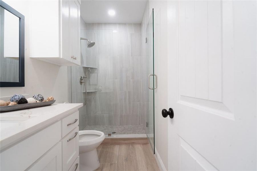 Bathroom featuring toilet, a stall shower, and vanity