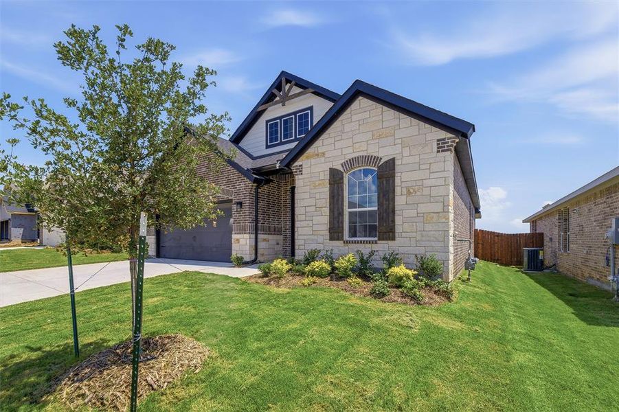 Exterior showcasing a mix of light-colored stone and dark brick, with a deep gray garage door Exterior showcasing a mix of light-colored stone and dark brick, with a deep gray garage door