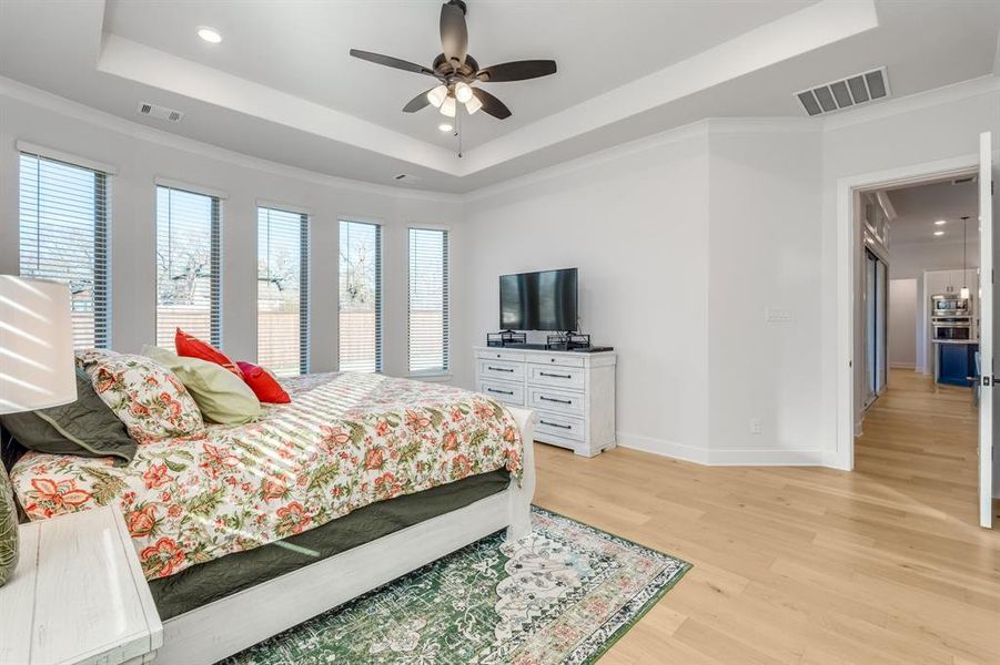 Bedroom with a tray ceiling, crown molding, ceiling fan, and light hardwood / wood-style floors