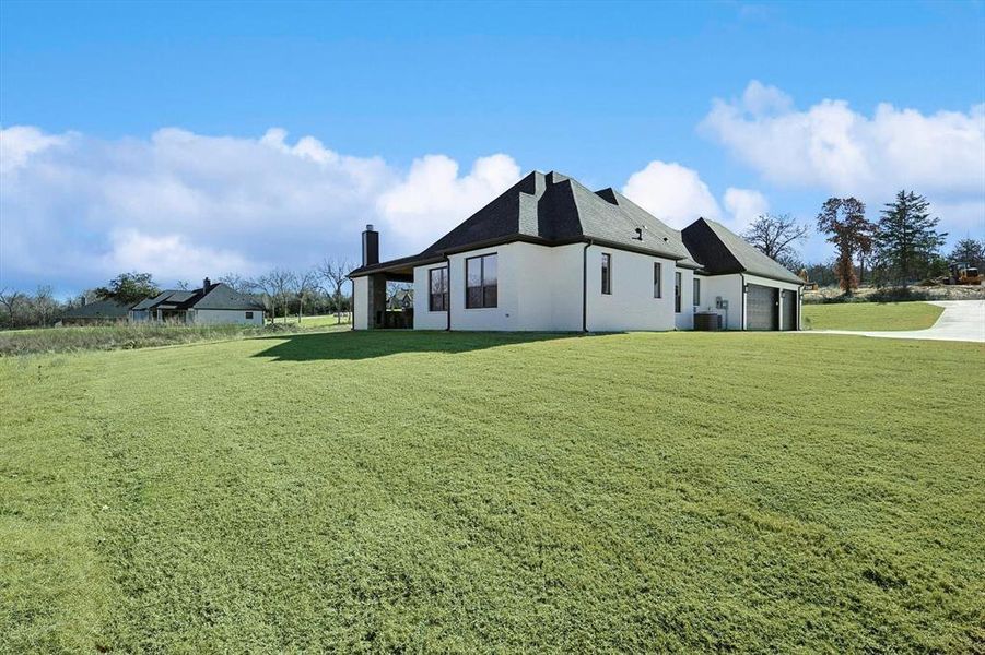 View of home's exterior with central air condition unit, a garage, and a lawn