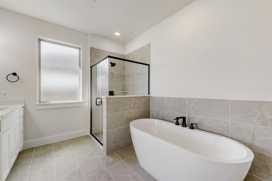 Full bathroom with a shower stall, vanity, a soaking tub, and tile walls