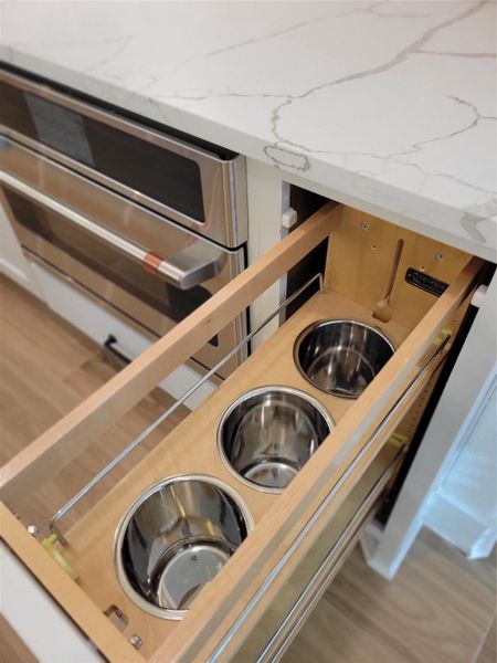 This kitchen photo showcases a modern, space-saving pull-out organizer with built-in stainless steel containers, ideal for storing utensils or spices. The setup is complemented by sleek stainless steel appliances and a quartz countertop, creating a stylish and functional cooking space. This kitchen photo showcases a modern, space-saving pull-out organizer with built-in stainless steel containers, ideal for storing utensils or spices. The setup is complemented by sleek stainless steel appliances and a quartz countertop, creating a stylish and functional cooking space.