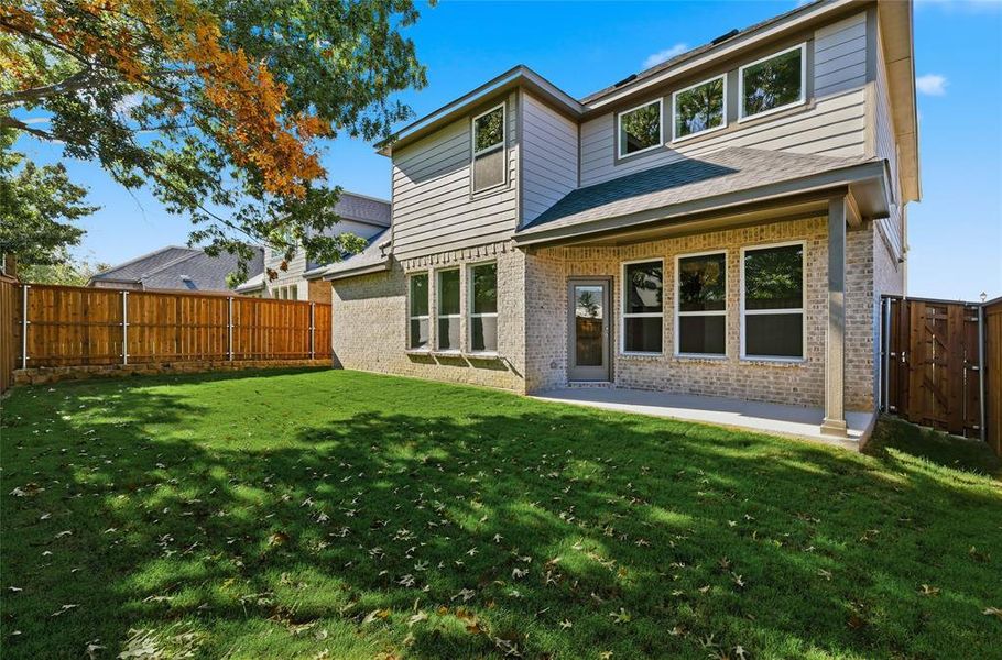 Rear view of house featuring brick siding, a patio, and a fenced backyard