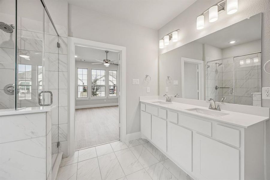 Full bath with double vanity, a marble finish shower, light marble finish floors, and a ceiling fan Full bath with double vanity, a marble finish shower, light marble finish floors, and a ceiling fan