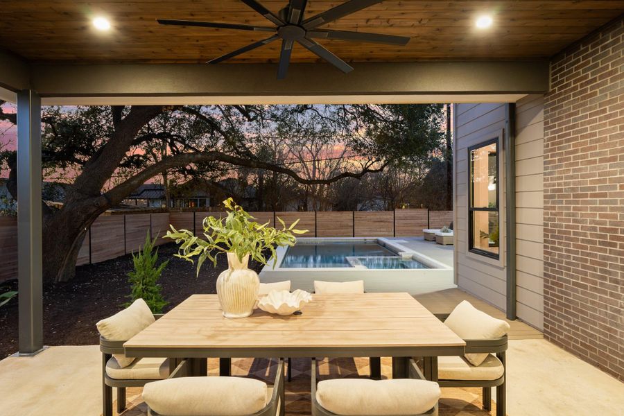 Fenced backyard with ceiling fan, a patio area, outdoor dining space, an outdoor hot tub, and a swimming pool