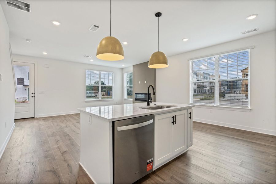 Kitchen island with a built-in stainless steel dishwasher, undermount sink, and matte black faucet