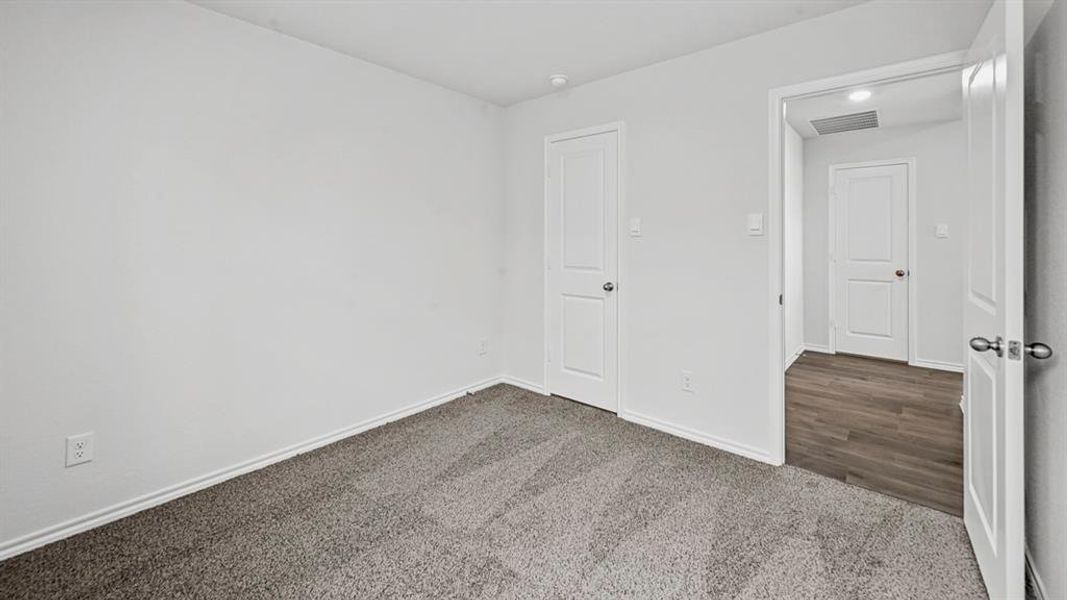 Carpeted interior room with white walls, white trim, and a white paneled door