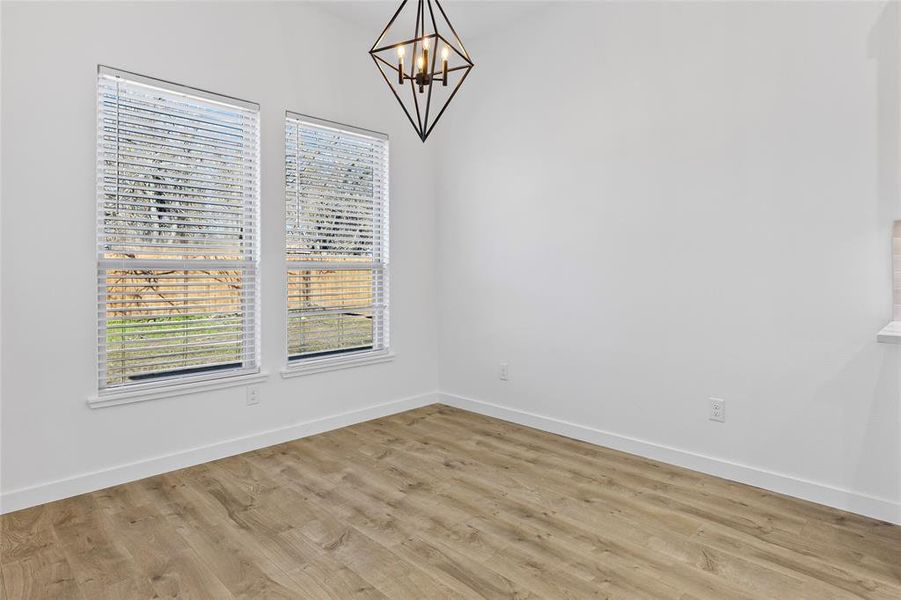 Unfurnished dining area with an inviting chandelier, light wood-style flooring, and baseboards