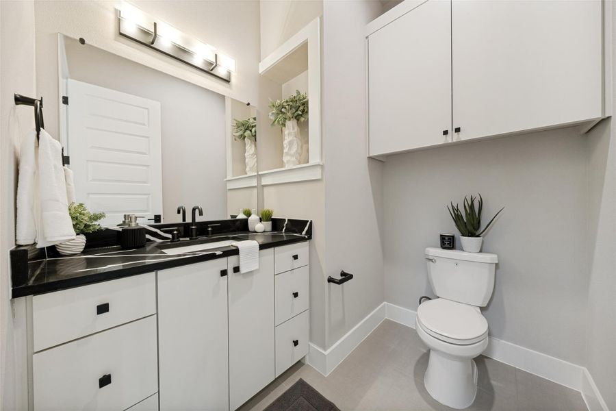 A well-appointed half bath boasts a modern vanity with elegant dark counters and integrated storage. A well-appointed half bath boasts a modern vanity with elegant dark counters and integrated storage.