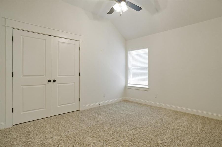 Unfurnished bedroom featuring ceiling fan, lofted ceiling, carpet flooring, and a closet