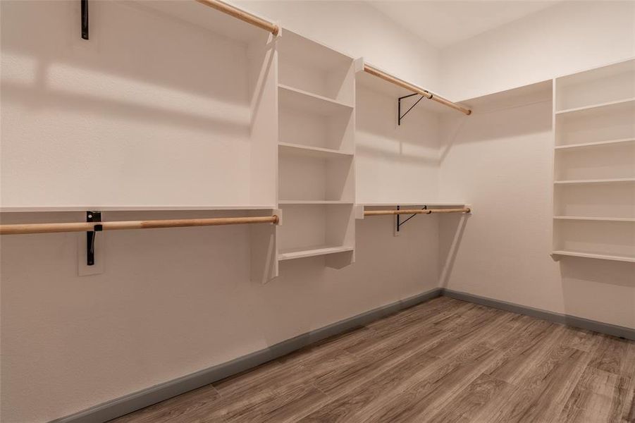 Walk in closet with wood-type flooring