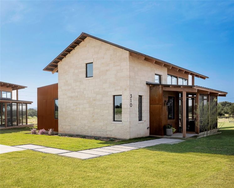 Modern Hill Country exterior with limestone facade, standing seam roof, and  patina metal finished accents creating a refined contemporary ranch aesthetic.