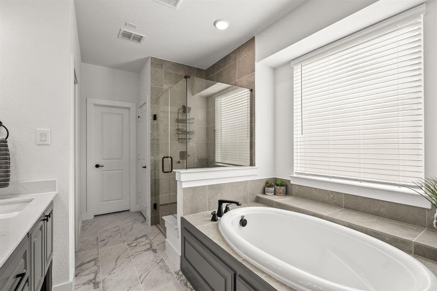 Full bath with vanity, a bath, a stall shower, and light marble finish floors Full bath with vanity, a bath, a stall shower, and light marble finish floors