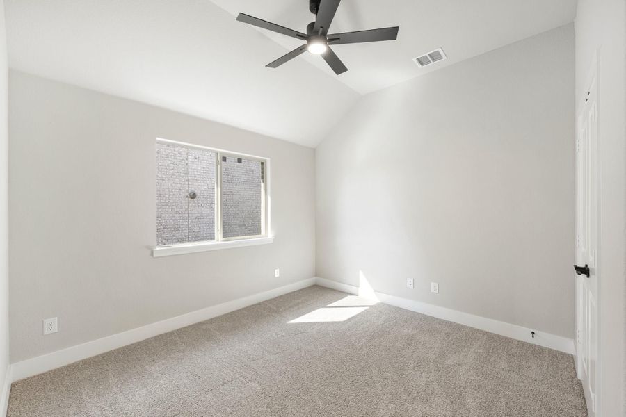 Empty bedroom with vaulted ceiling, ceiling fan, carpet flooring, and a single window