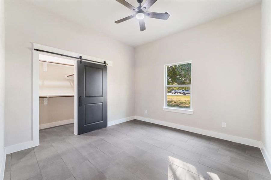 Bedroom #2 features a ceiling fan with reversible blades for a choice of black or wood-look finish, a wall outlet for your mounted TV and a sliding barn door leading to your spacious walk-in closet.