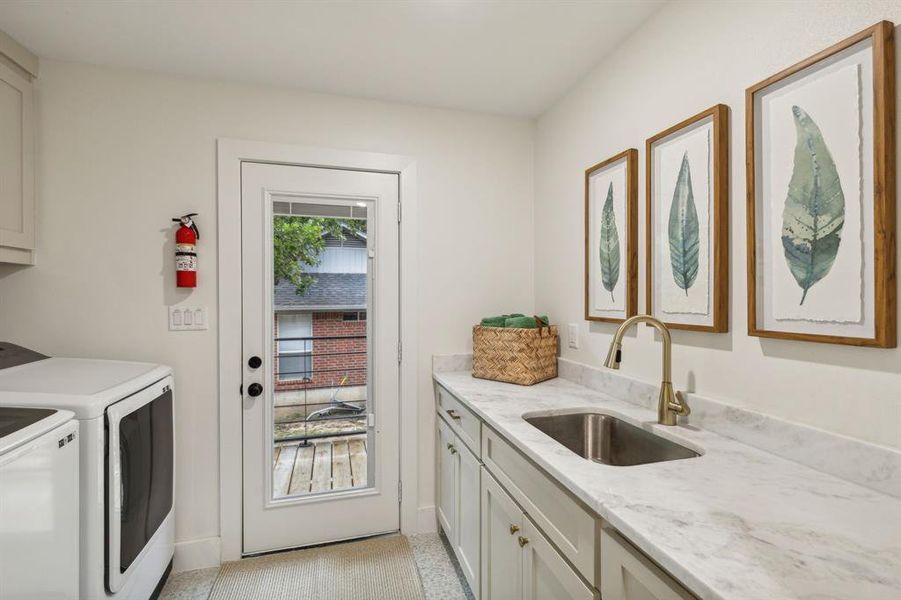 Kitchen featuring separate washer and dryer, sink, light tile flooring, and light stone countertops