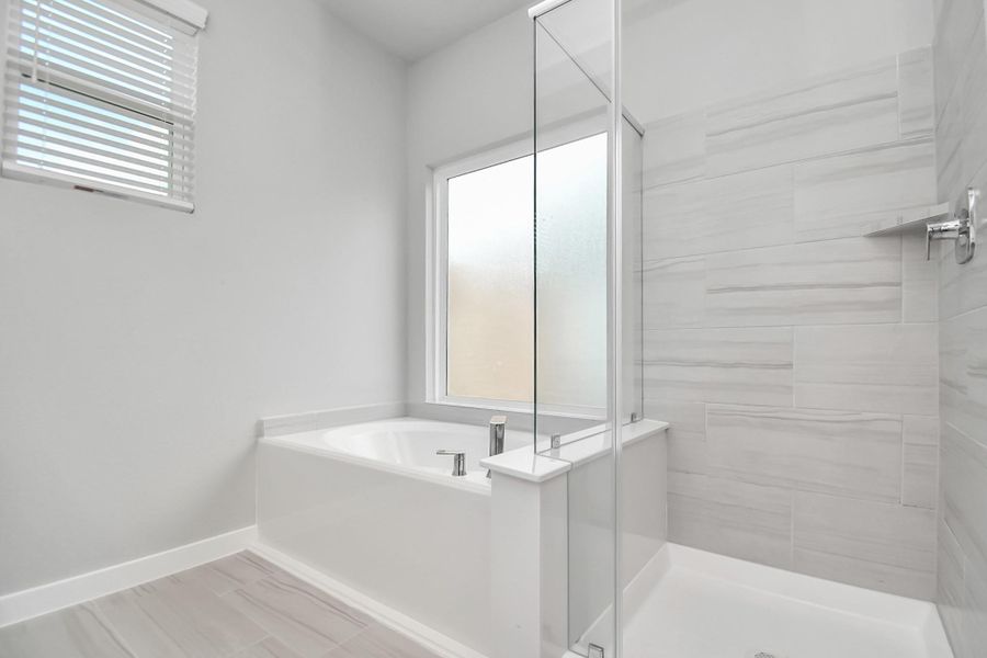 This additional view of the primary bath features a walk-in shower with the tile surround and separate garden tub perfect for soaking after a long day. Sample photo of completed home with similar floor plan. Actual colors and selections may vary.