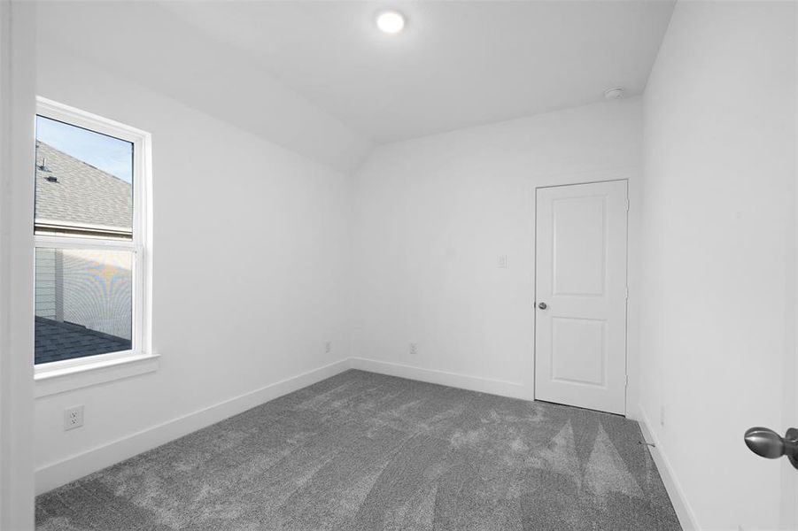 Carpeted empty room with vaulted ceiling