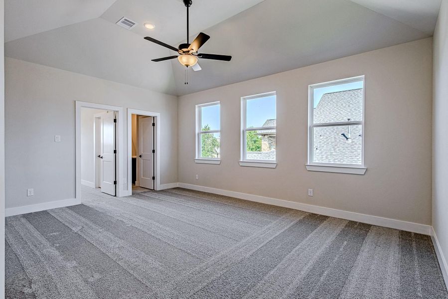 Large upstairs game room with a ceiling fan and multiple windows