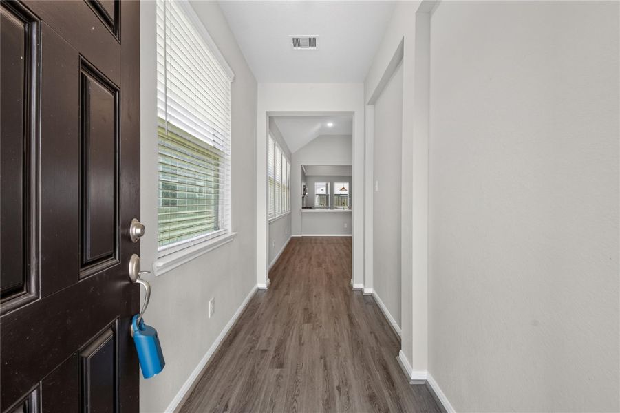 This photo showcases a bright, welcoming entryway with wood-style flooring, neutral walls, and ample natural light from side windows, leading into the main living area. This photo showcases a bright, welcoming entryway with wood-style flooring, neutral walls, and ample natural light from side windows, leading into the main living area.
