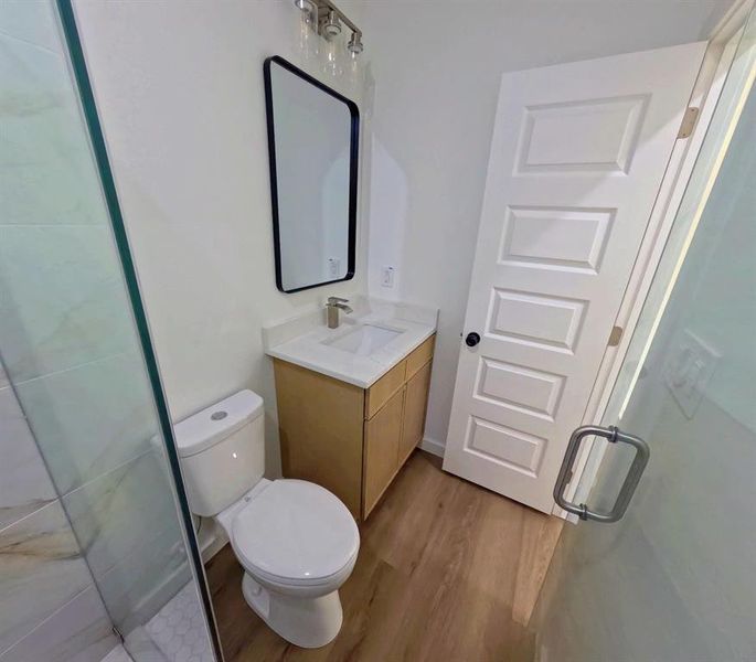 Bathroom with dark wood-style flooring, vanity, and a shower stall Bathroom with dark wood-style flooring, vanity, and a shower stall