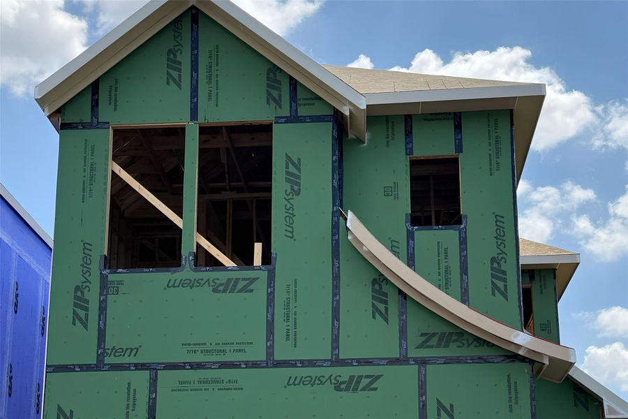 New construction home under development showcases structural framing and weatherproofing sheathing against a blue sky.