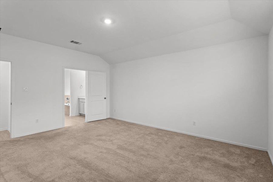 A spacious, neutral-toned room with vaulted ceilings and a clear view into an adjacent bathroom. A spacious, neutral-toned room with vaulted ceilings and a clear view into an adjacent bathroom.