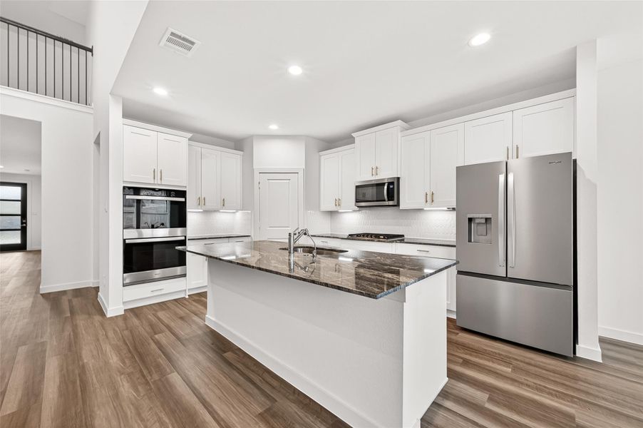 Kitchen:  A gorgeous island kitchen with quartz countertops, an undermount stainless steel sink, sleek white cabinetry with brushed nickel hardware, pull-out pot drawers, and a walk-in pantry with built-in shelving. Stainless steel built-in appliances, including a double oven and gas cooktop, pair perfectly with the stylish tile backsplash.