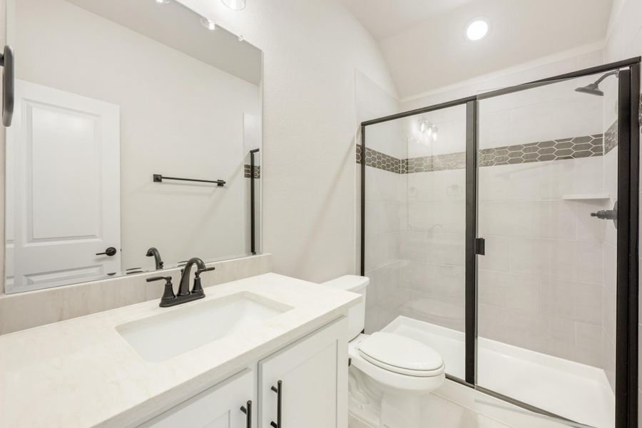 Bathroom with white vanity, glass shower with tile accent strip, and black hardware fixtures