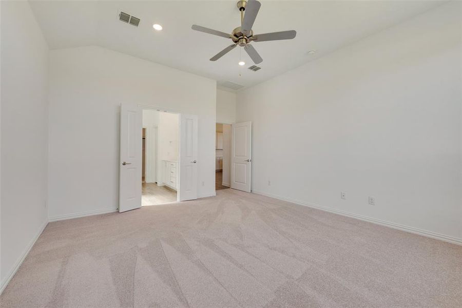 Unfurnished bedroom with ensuite bathroom, ceiling fan, light carpet, and lofted ceiling