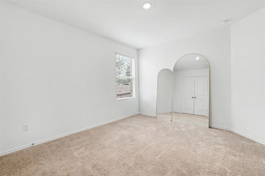 Carpeted room with a window featuring horizontal blinds