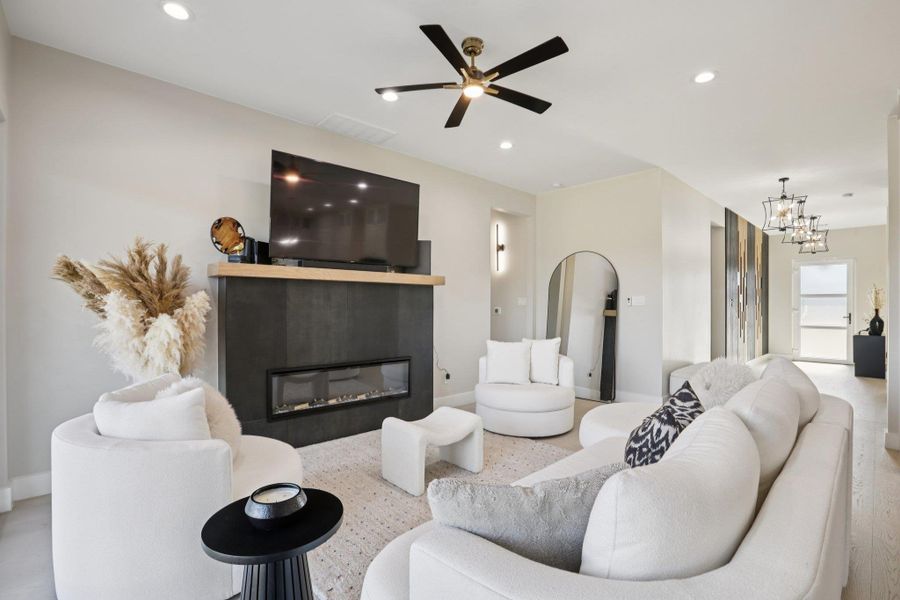 Living room featuring a ceiling fan, a glass covered fireplace, arched walkways, and hanging lights