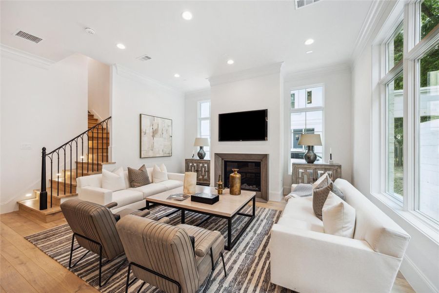 The expansive living room features an elegant 42” fireplace with herringbone tile design, wrought iron stairway detail, LED integrated recessed lighting and Pella Lifestyle windows. The expansive living room features an elegant 42” fireplace with herringbone tile design, wrought iron stairway detail, LED integrated recessed lighting and Pella Lifestyle windows.