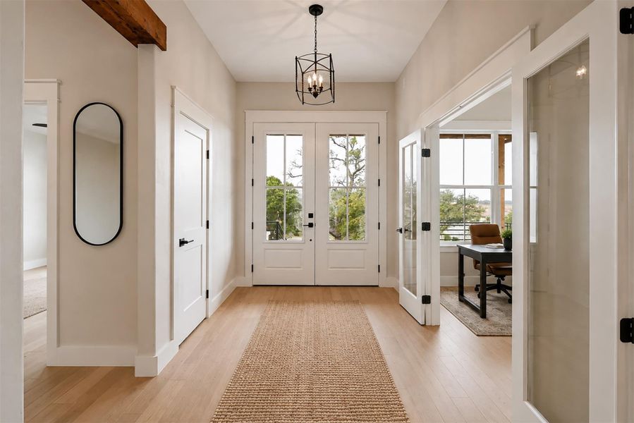 An inviting entryway features warm wood flooring, a rustic ceiling beam, and classic French doors. An inviting entryway features warm wood flooring, a rustic ceiling beam, and classic French doors.