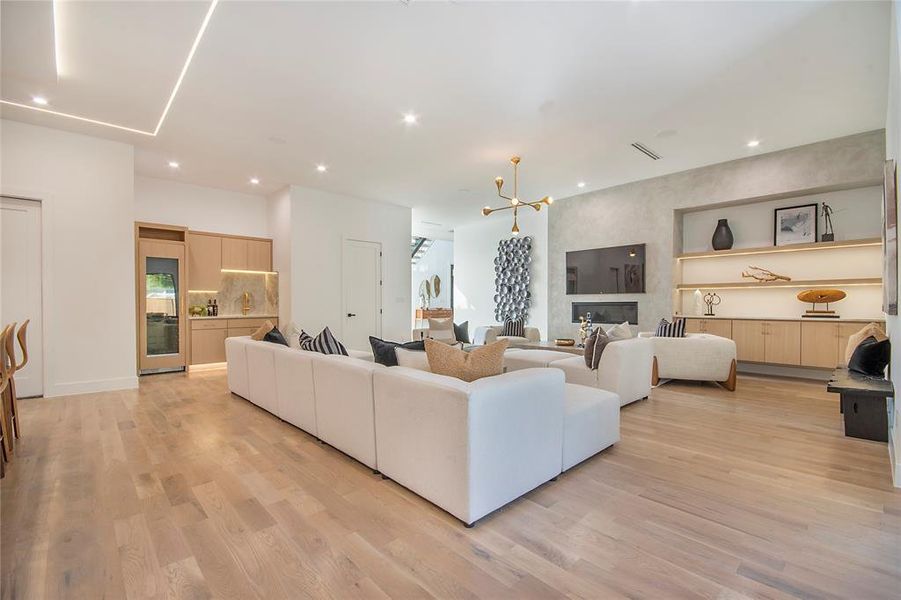 Living area featuring a chandelier, light wood finished floors, wine cooler, and recessed lighting