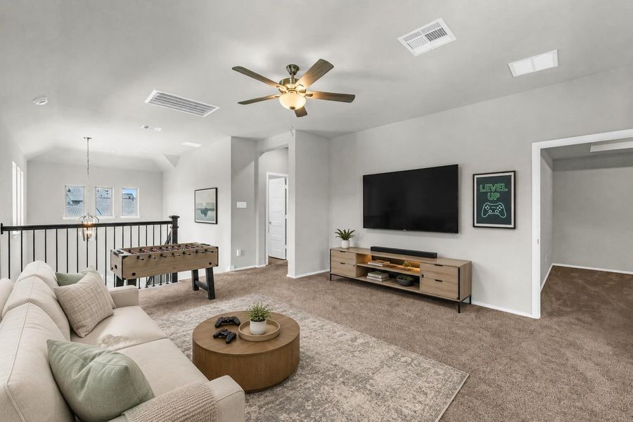 An expansive upstairs game room features soft carpeting, a central ceiling fan, and iron stair railings overlooking the lower level.**Virtually staged An expansive upstairs game room features soft carpeting, a central ceiling fan, and iron stair railings overlooking the lower level.**Virtually staged