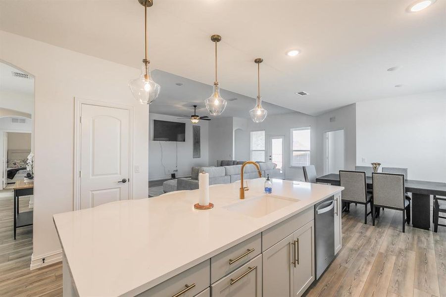 Kitchen featuring dishwasher, a kitchen island with sink, hanging light fixtures, sink, and ceiling fan