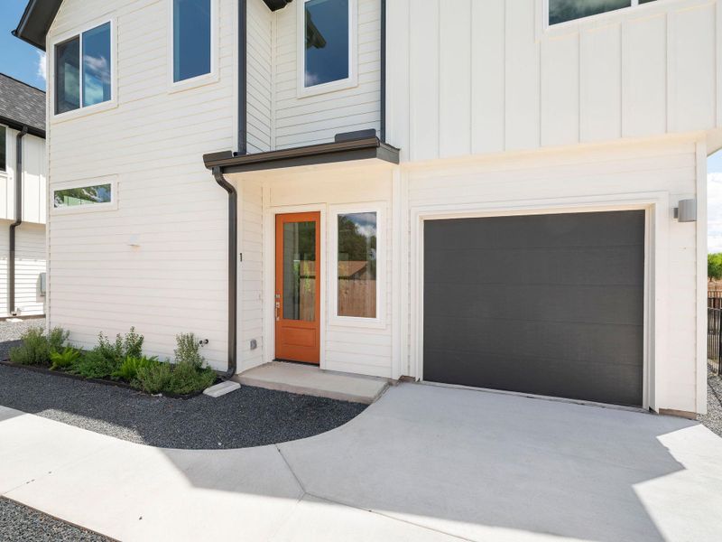 Modern facade with a rich wood entry door and an integrated single-car garage.
