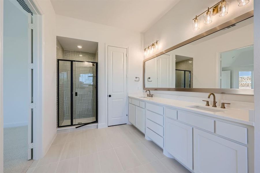 Bathroom with tile patterned flooring, a shower with door, and vanity