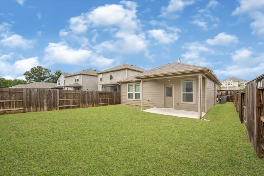 Clean exterior view showing the side and rear structure of the home within the fully enclosed yard.