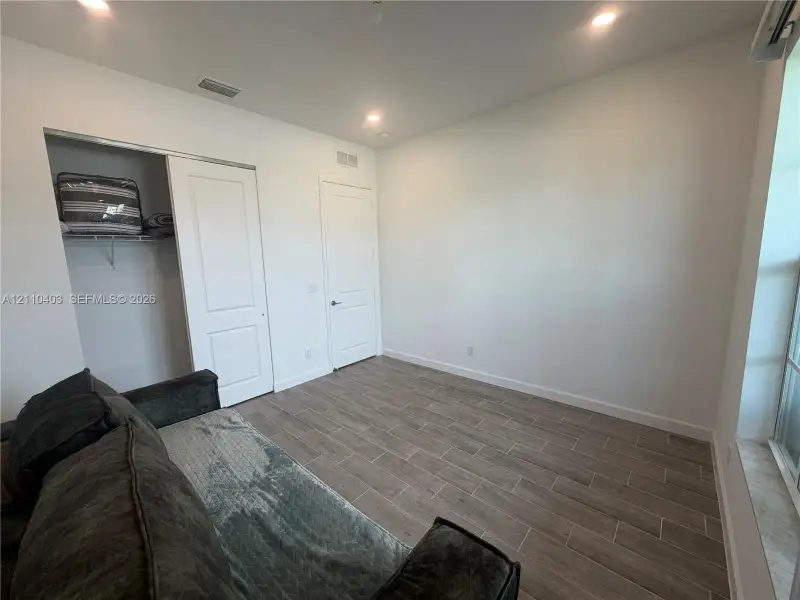 Room featuring wood-finish tile flooring, recessed lighting, a sliding closet door, and a multi-panel interior door