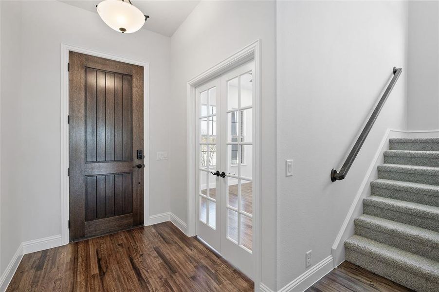Entryway with stairs, dark wood-type flooring, and french doors