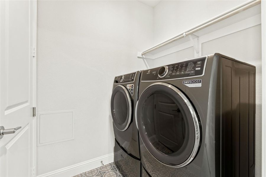 Laundry room with front-load washer and dryer set, overhead shelf, and patterned tile floor