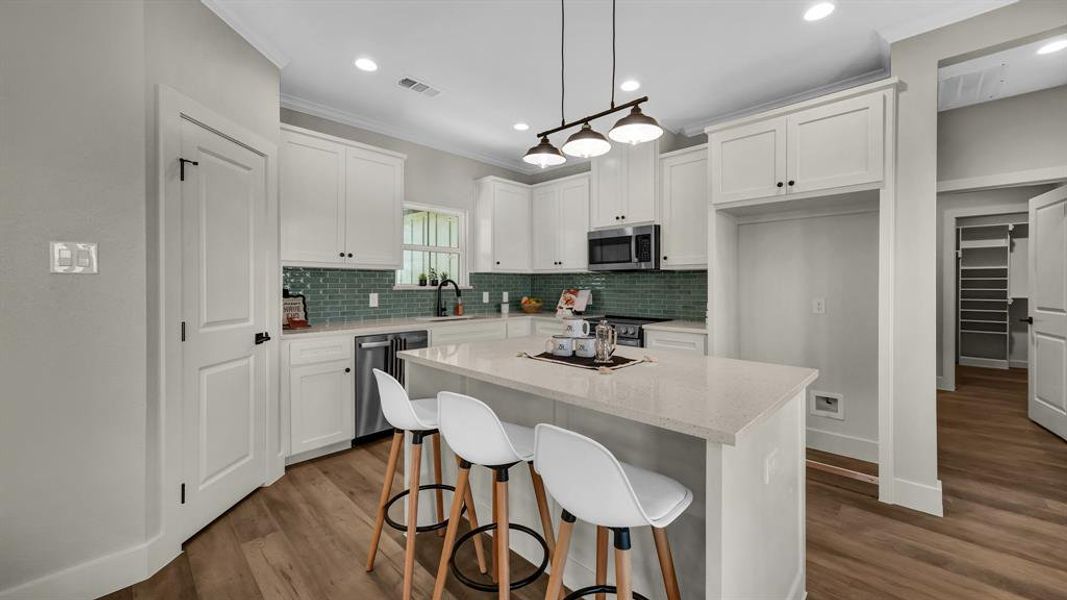 Kitchen with white cabinetry, dark wood-style flooring, a kitchen island, a breakfast bar, and recessed lighting