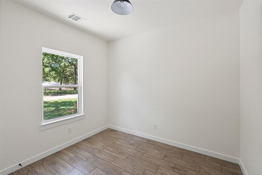 Room with light wood-finish flooring, white walls, and a single-pane window